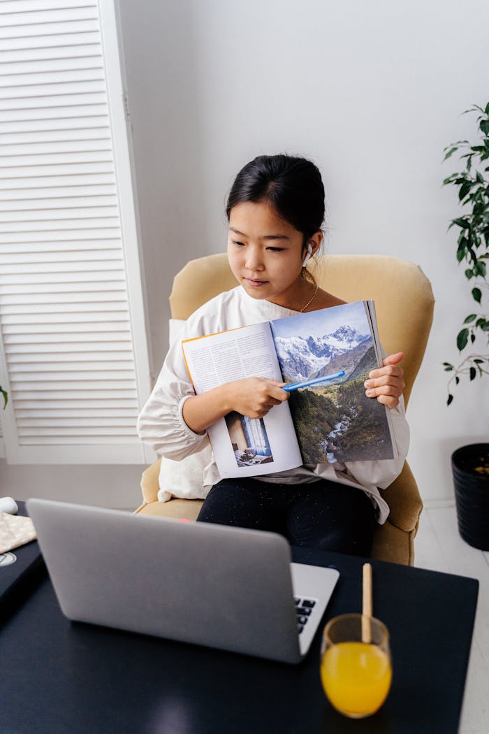 Asian woman demonstrates teaching via video call, showing a book page.